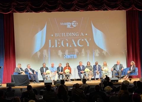 Panel of ten people on stage with a backdrop saying "Building a Legacy."